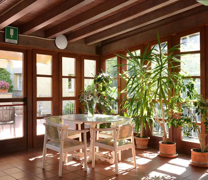 Spazio interno della RSA con area relax, tavolo, sedie e piante